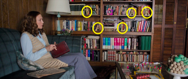 A woman sits next to a bookshelf with letters spelling out VALAK