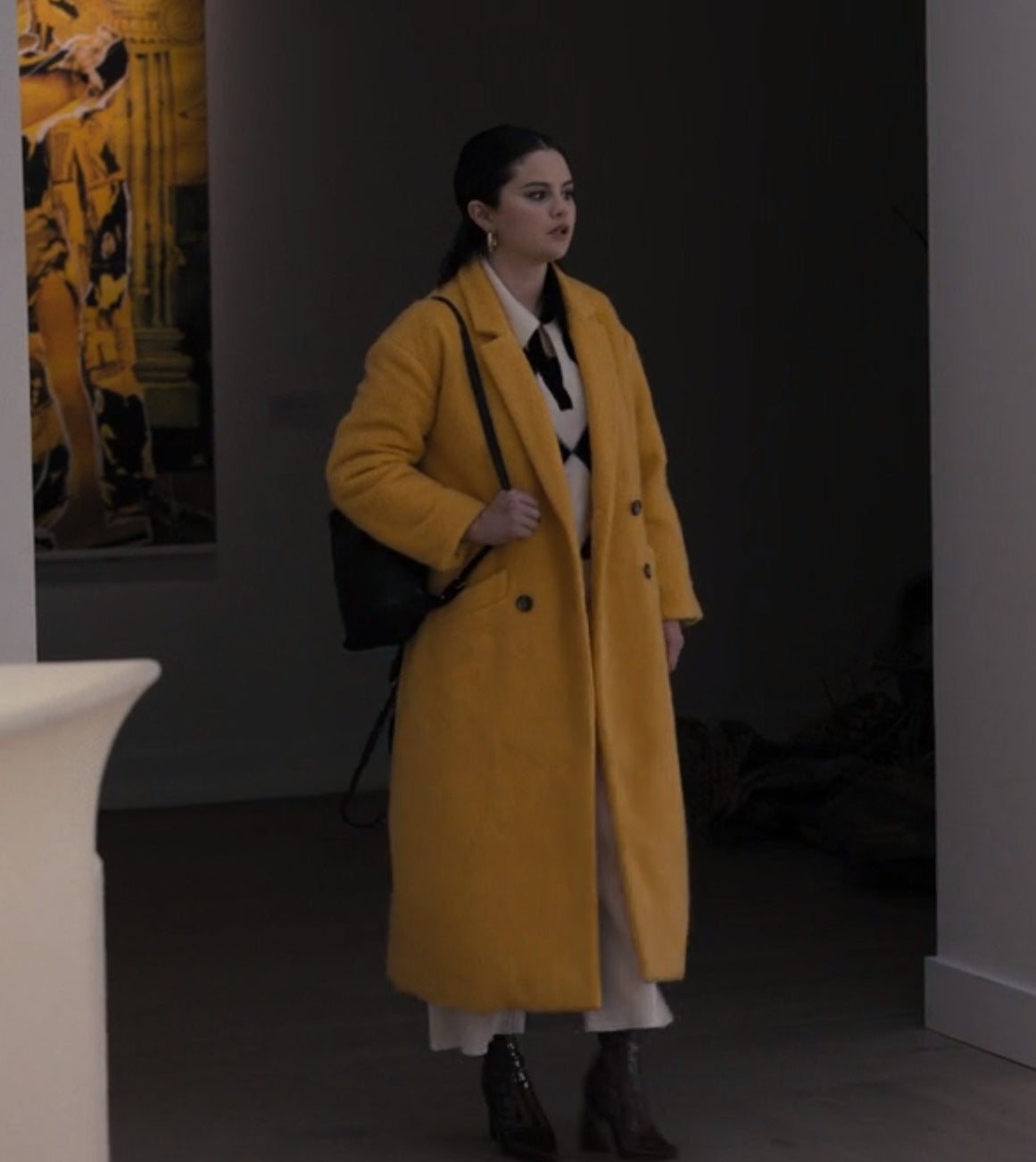 Mabel walking in an art gallery in a yellow coat