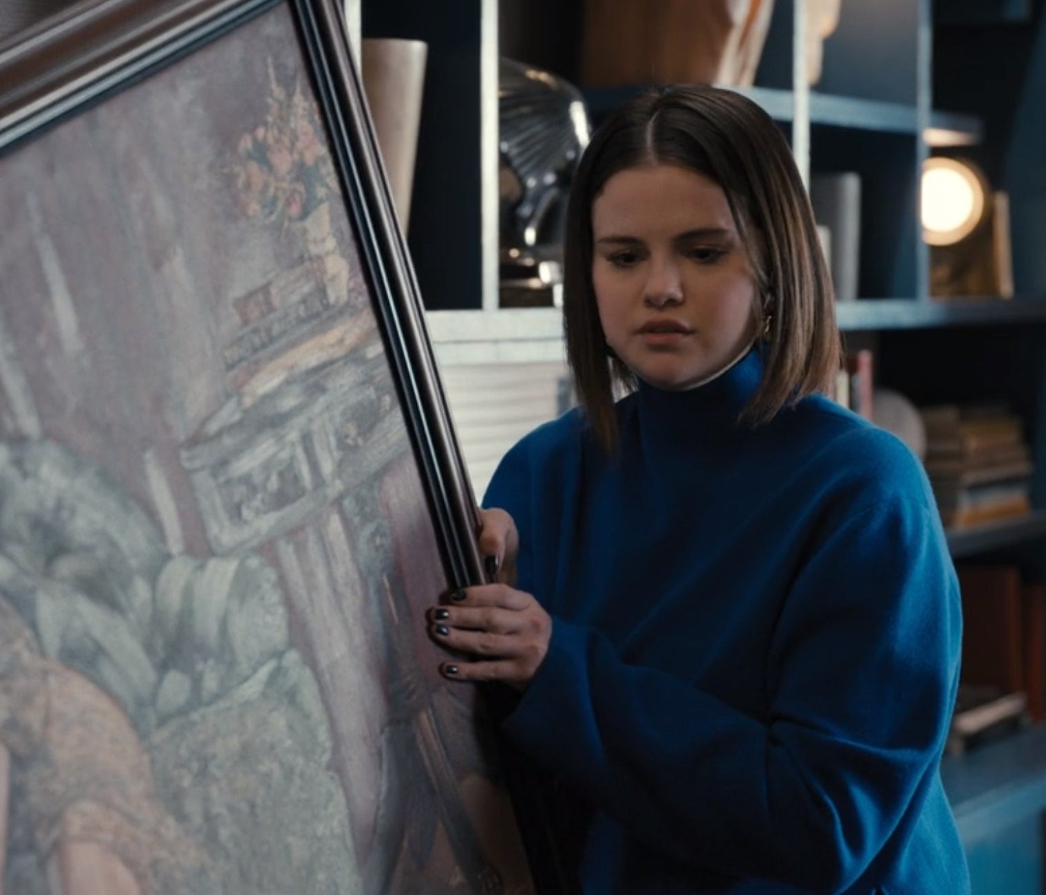 Mabel holding a painting in a blue sweater