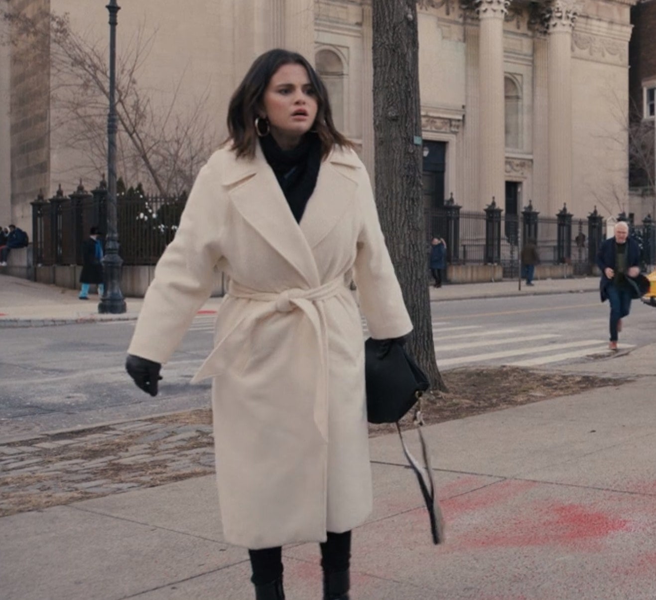Mabel walking on the street in a white coat