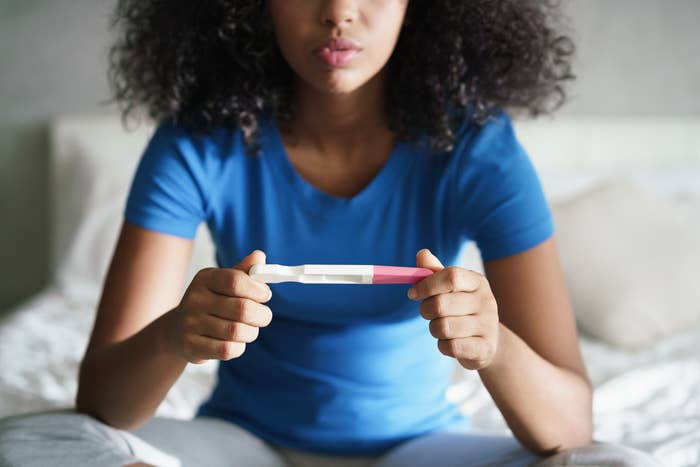 A young girl holding a pregnancy test
