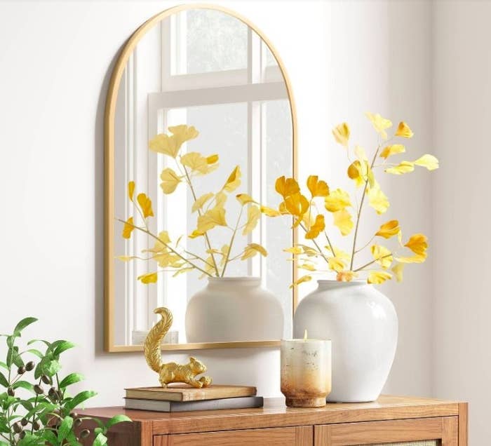 Brass mirror above styled wood console