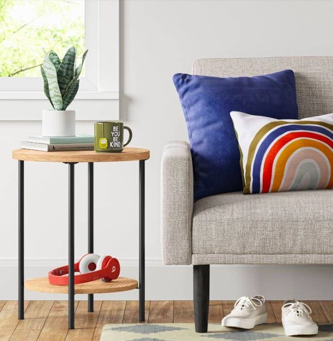 End table with books, a plant and a mug on top, next to a sofa