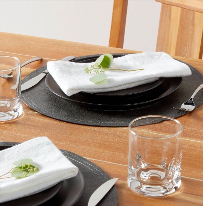 White napkins with a eucalyptus stem on black plates