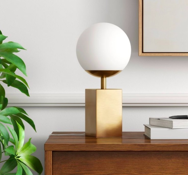 Gold globe lamp sitting on a wood console next to books