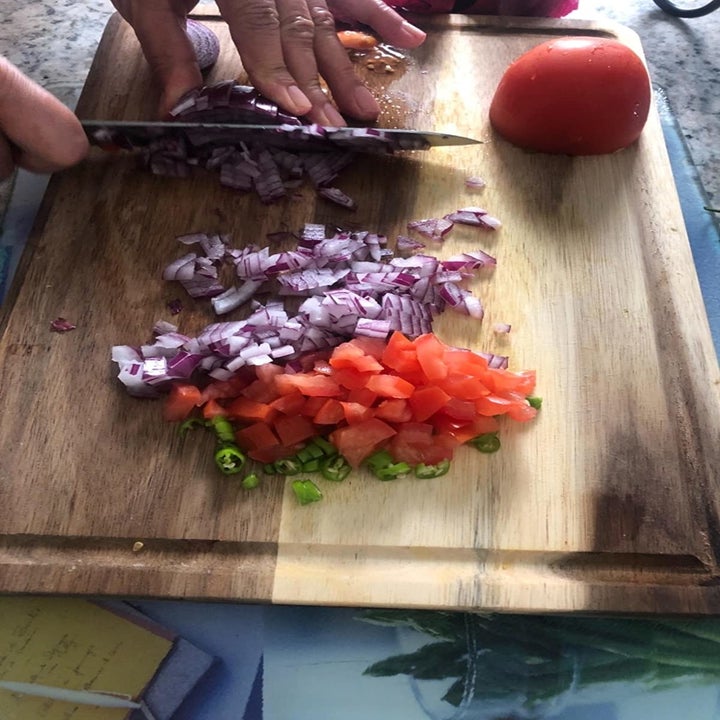 Reviewer chopping onion, tomato and pepper on the wood cutting board