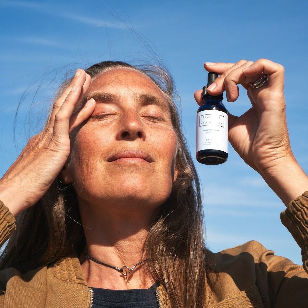 a person holding a bottle of brow serum outdoors