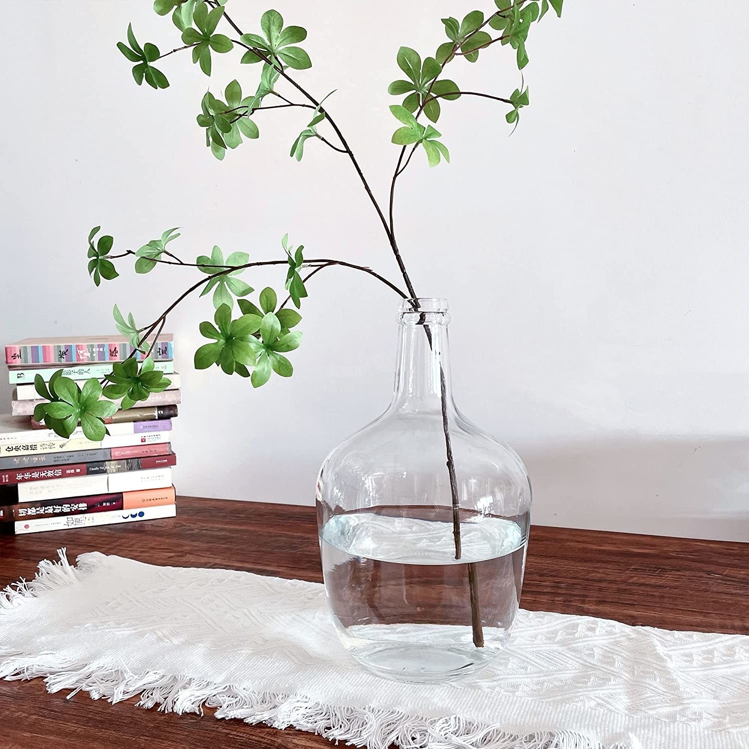 a glass balloon vase with a fresh leafy branch inside