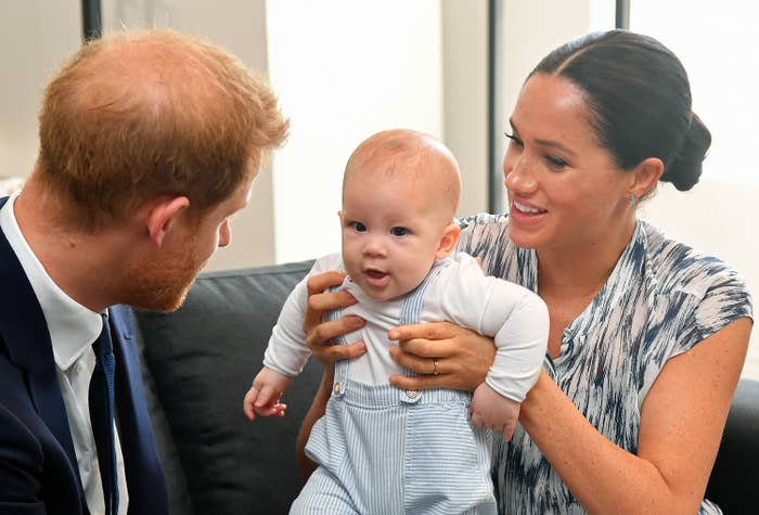 Megan holds up baby Archie while he looks at his dad Prince Harry