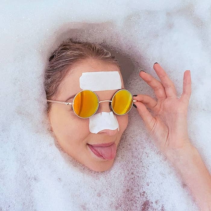a person wearing sunglasses in a bubble bath with strips on their nose and forehead