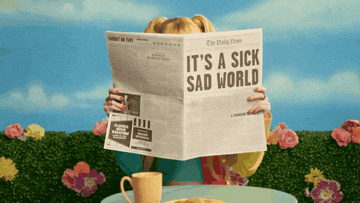 person reading newspaper that says it&#x27;s a sick sad world