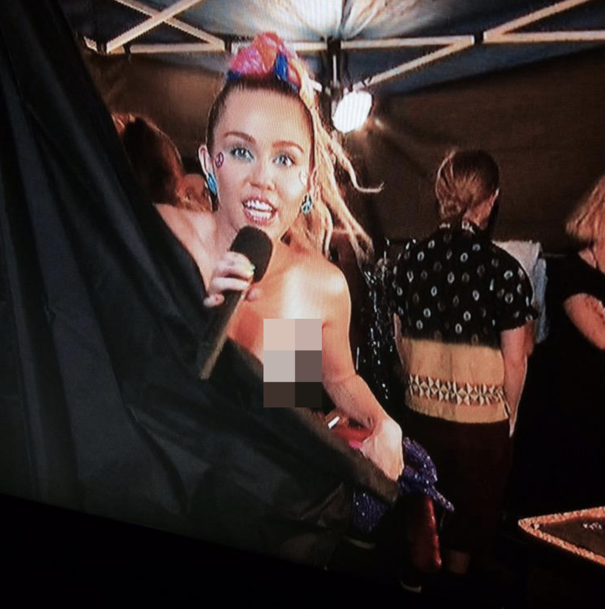 Miley behind the curtain with her exposed breast pixelated