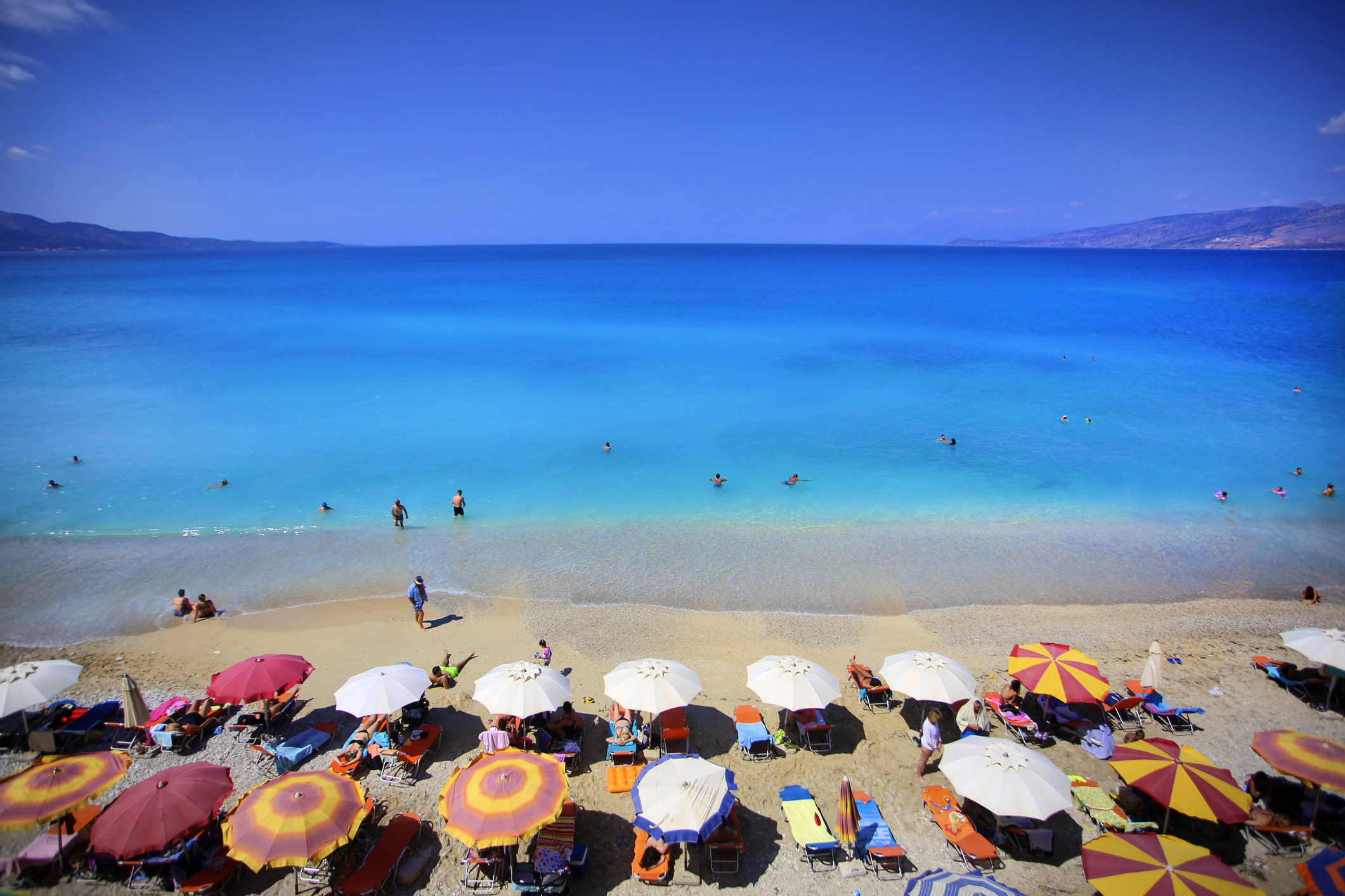 A very colorful beach with umbrellas in the sand.