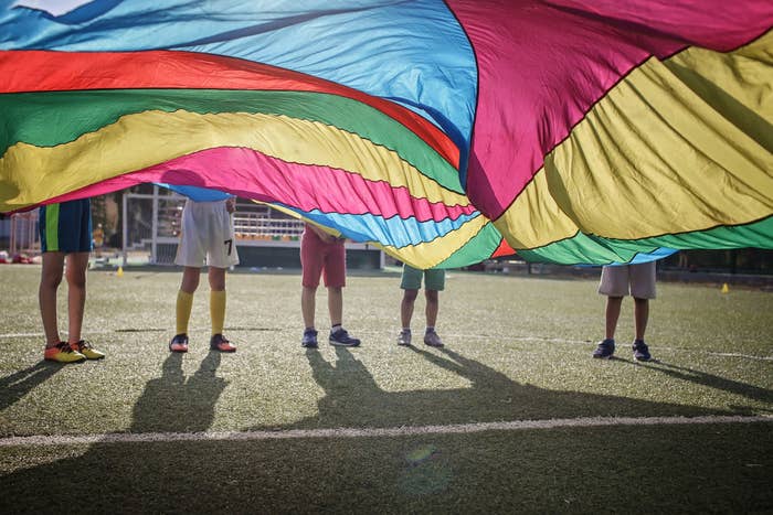 kids playing with a rainbow parachute