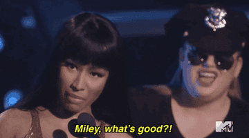 Nicki saying into a microphone, &quot;Miley, what&#x27;s good?!&quot;