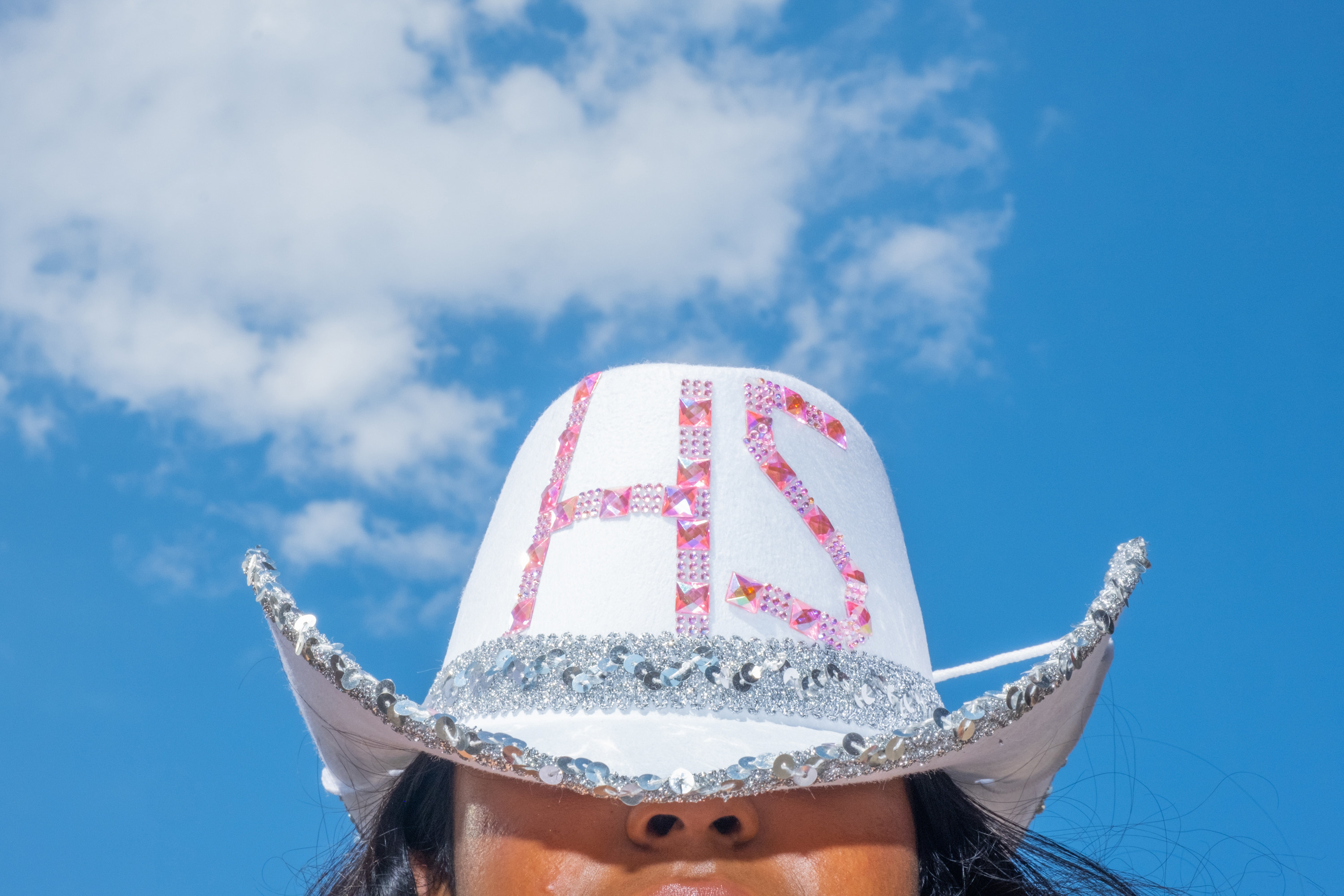 a bedazzled white cowboy hat that reads &quot;HS&quot; in pink letters