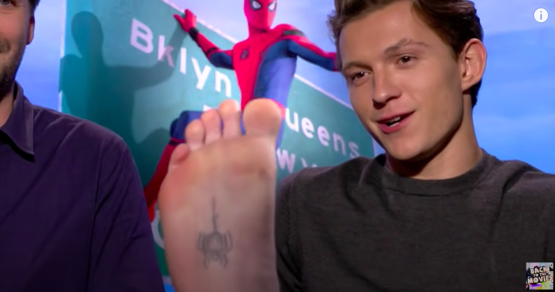 Tom with his foot raised showing the tat on the heel of his foot