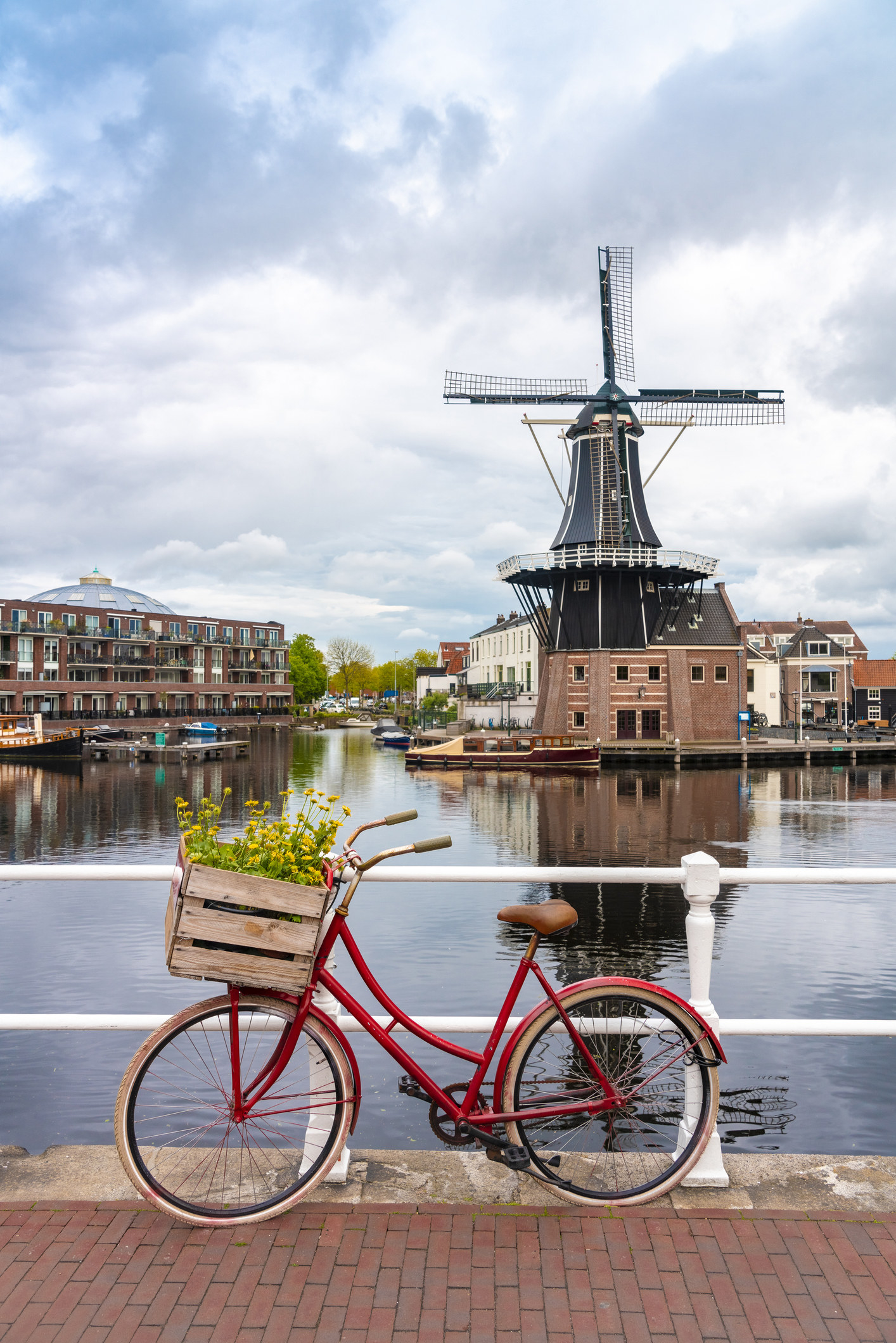A bicycle by a canal with windmill in the background.
