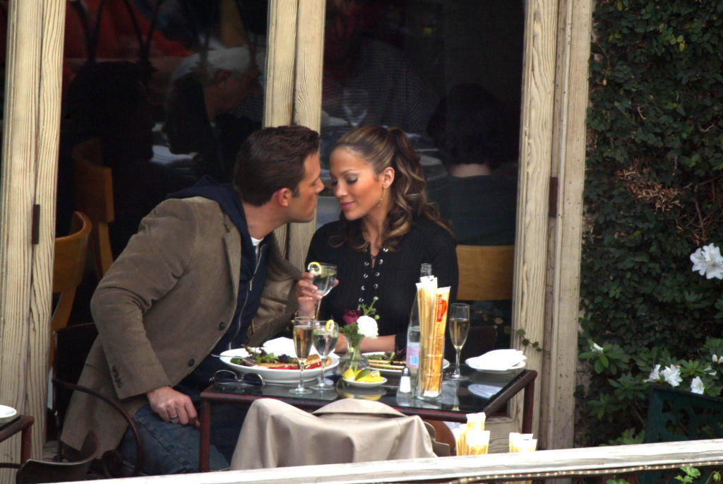 Jen and Ben eating outside as Ben leans in for a kiss