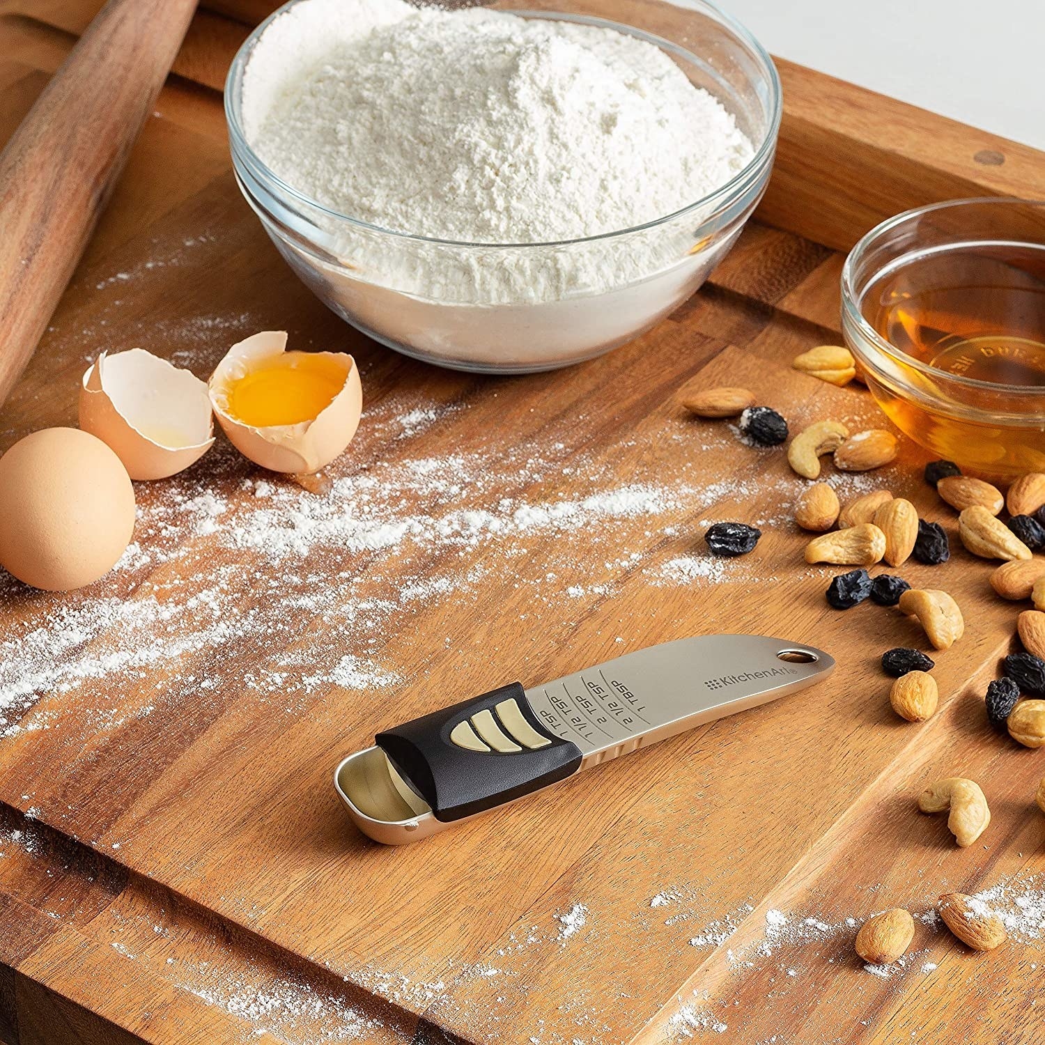 The measurement spoon on a wooden board surrounded by nuts, flour, and eggs