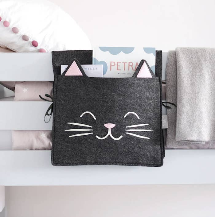 a cat-shaped felt bedside organizer tugged into the frame of a bunk bed