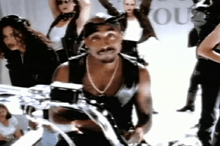 Tupac shrugs on a motorcycle in his &quot;All About U&quot; music video