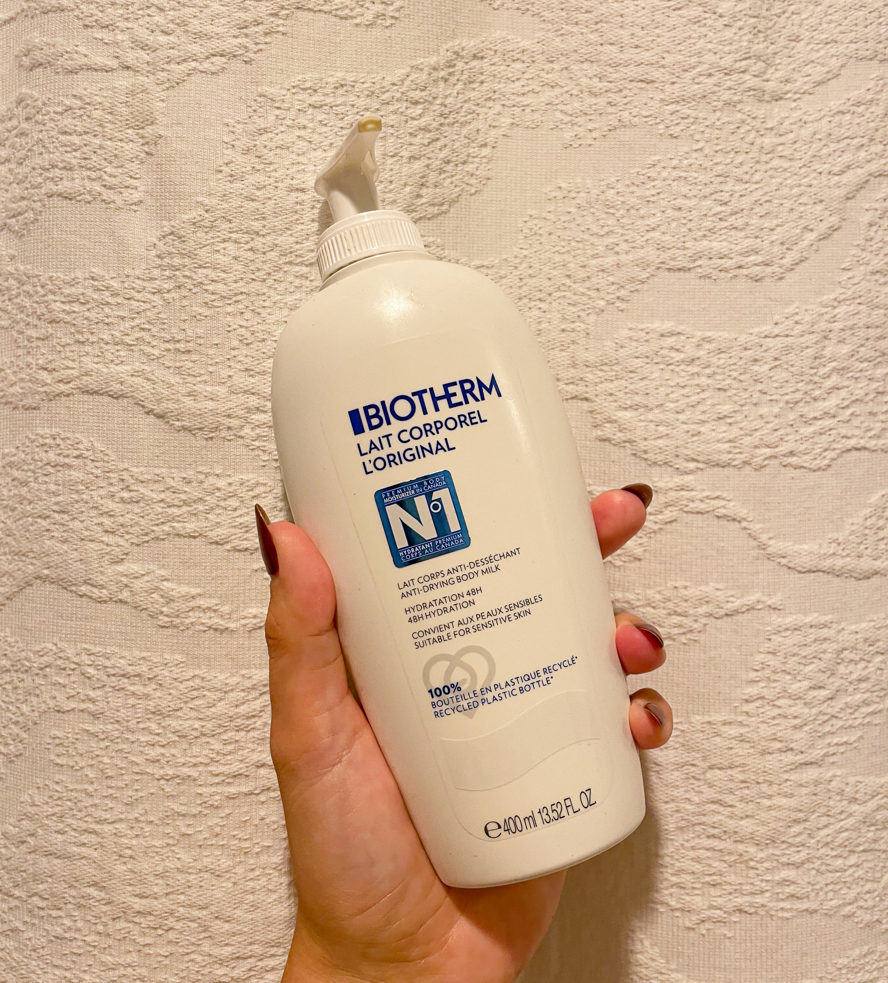 Victoria holding up a bottle of the biotherm lotion