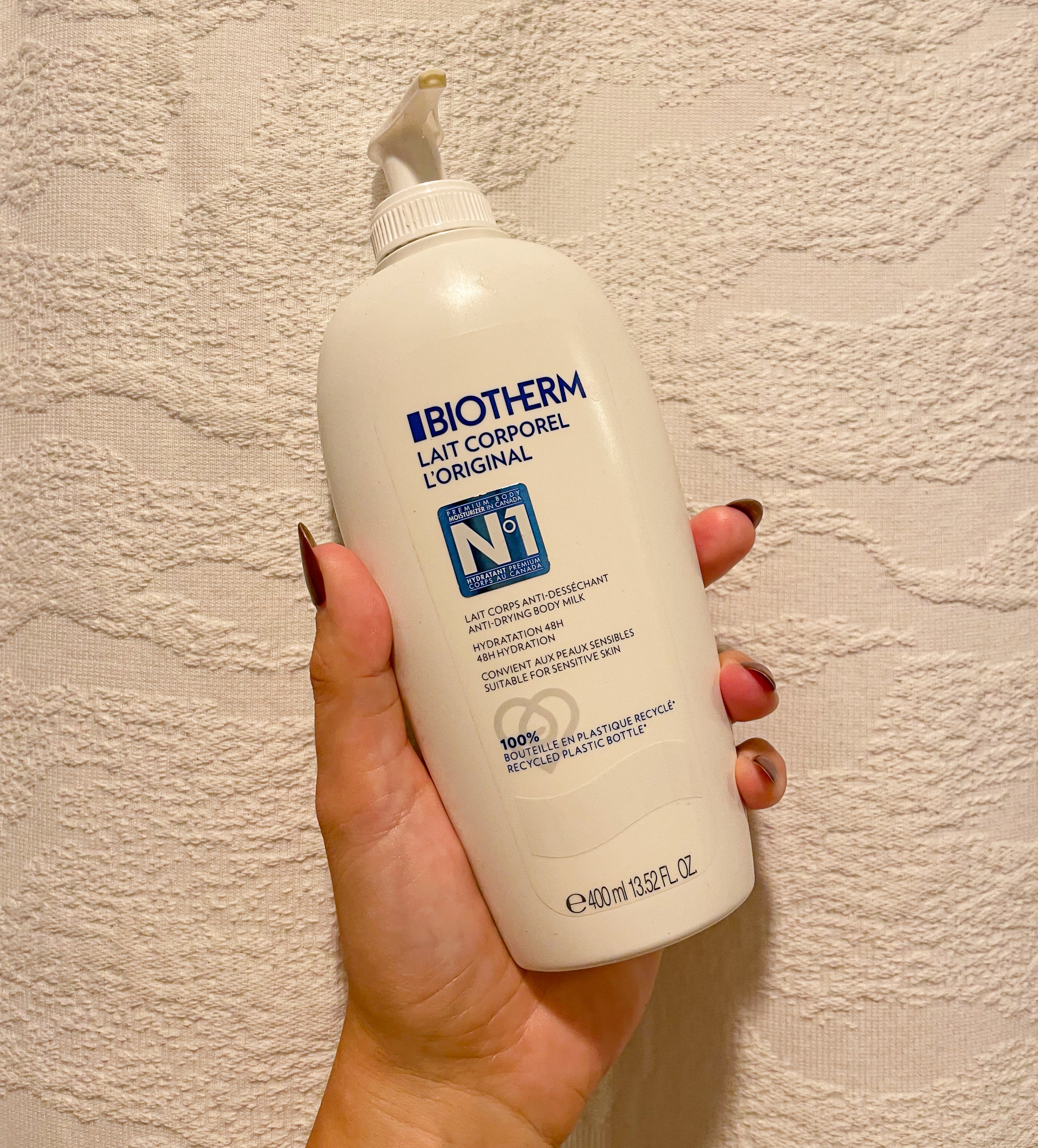 Victoria holding up a bottle of the biotherm lotion