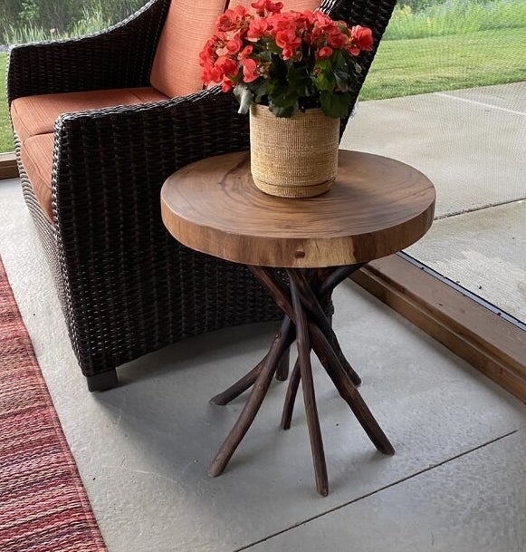 a reviewer photo of the table next to a wicker chair with a flower pot on top