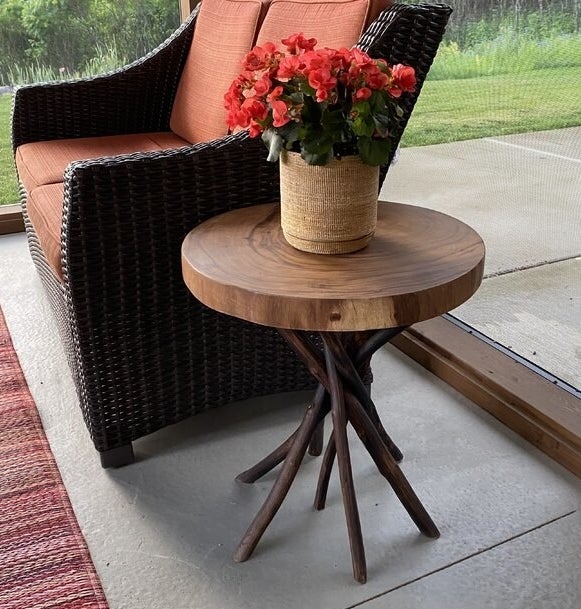 a reviewer photo of the table next to a wicker chair with a flower pot on top