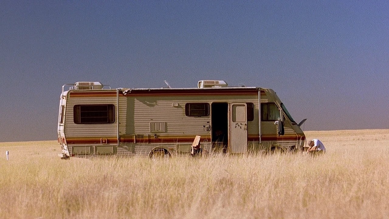 A still from Breaking Bad, of an RV parked in the middle of a desolate field