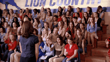 a group of girls raising their hands in a school gym