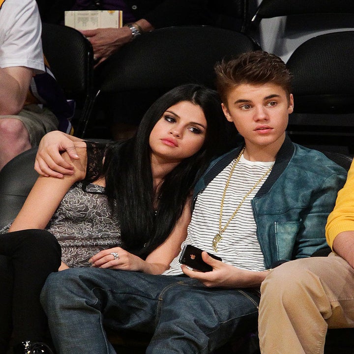justin with his arm around selena at a game