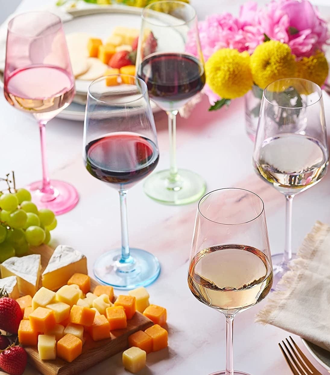 the wine glasses on a table next to a cheese platter