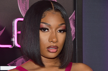 Megan Thee Stallion wears a fuchsia dress with cutouts with her hair in a bob and a pink smoky eye.