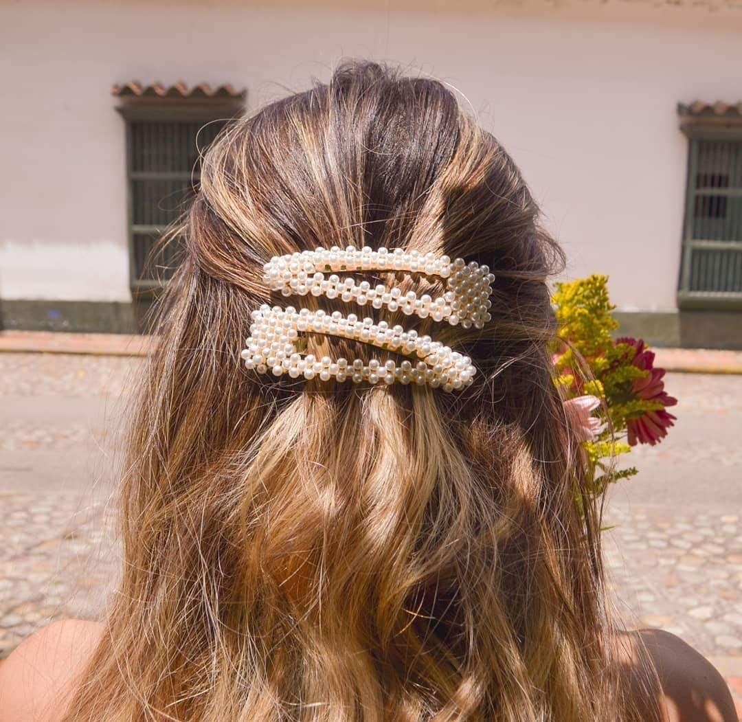 A person with two pearl barrettes in their hair