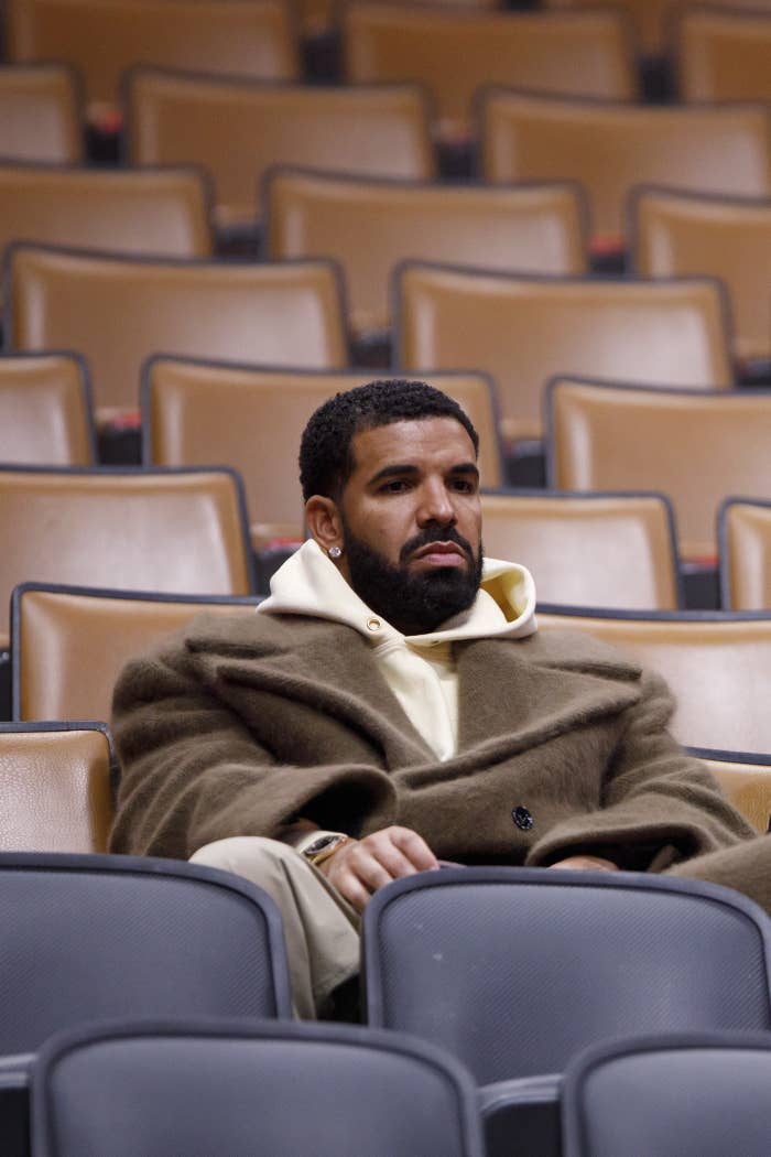 Drake sitting by himself in an auditorium, wearing a coat