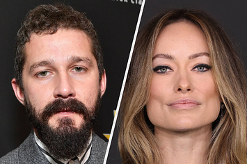 Shia LeBeouf wears a plaid suit in the color gray with a full beard. Olivia Wilde wears a black top with a beaded detailing around the neck with her hair in beach waves and dark eyeliner around her eyes.