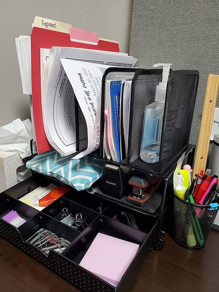 a reviewer&#x27;s desk organizer in black holding notebooks, folders, tape, stapler, sticky notes, clips, and hand sanitizer