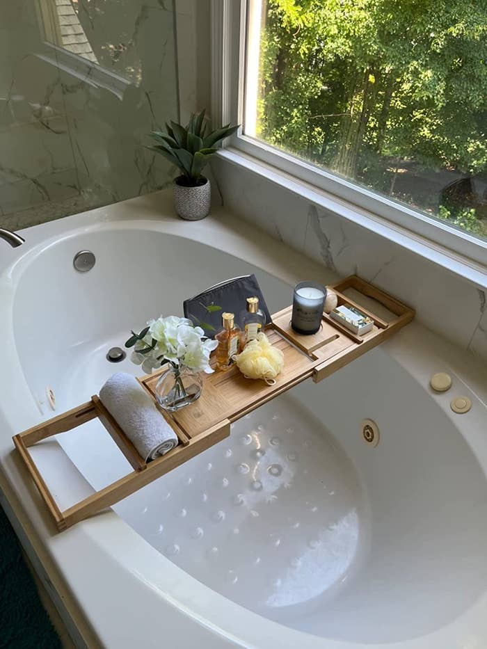 Reviewer image of bamboo tray with various accessories placed on a bathtub