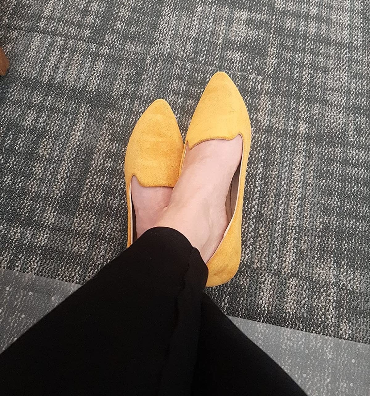 Reviewer wearing yellow pointed toe ballet flats