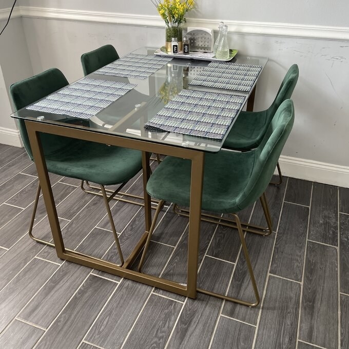 a reviewer photo of the glass and metal table with four green chairs