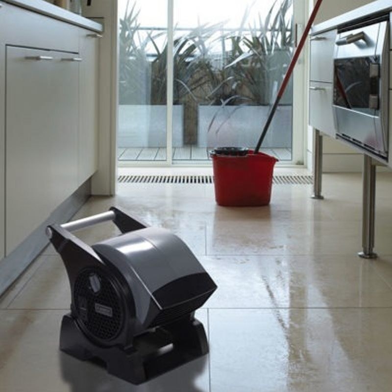 a black three-speed velocity fan drying a kitchen floor