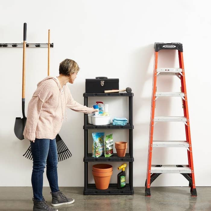 a person taking an item off a black four-shelf organizational system