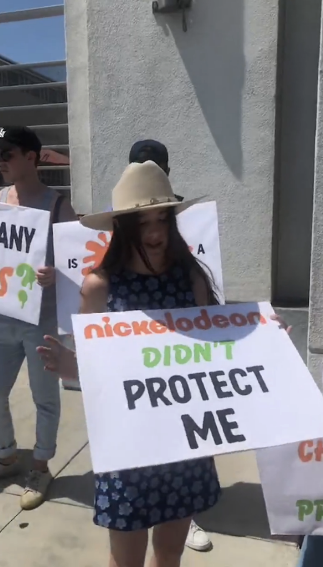 alexa and her sign that reads nickelodeon did not protect me