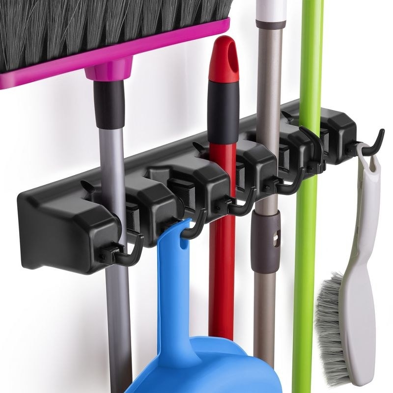 a five-slot wall organizer mount holding a broom, brush, mop, and dust pan
