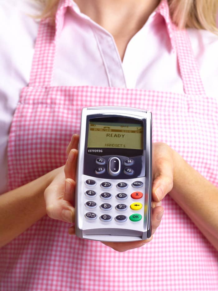 A woman holding out an EFTPOS machine in her hands