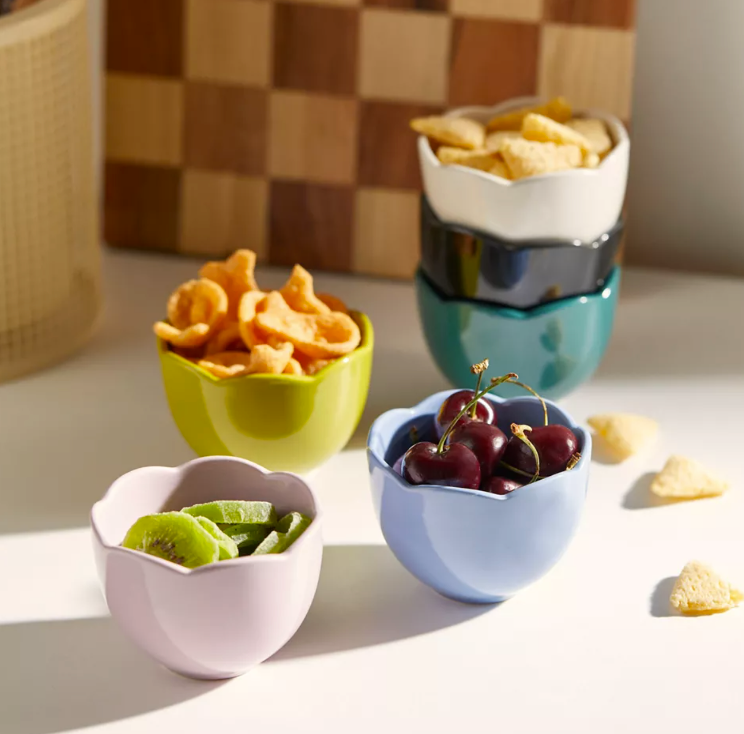 Six pinch bowls on a counter, three with fruit and snacks in them