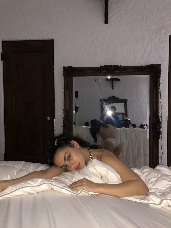charli xcx lays on a duvet, just wearing her underwear. she wears no makeup