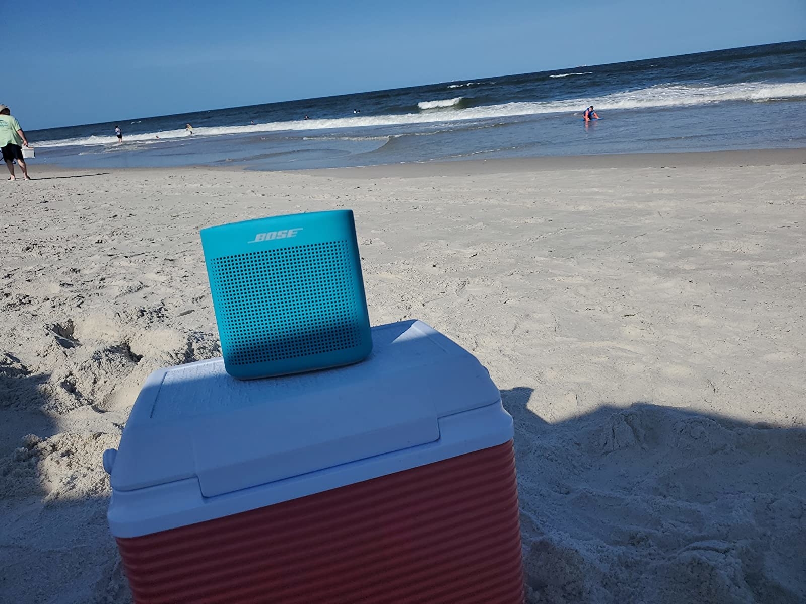 The blue speaker propped up on a cooler at the beach